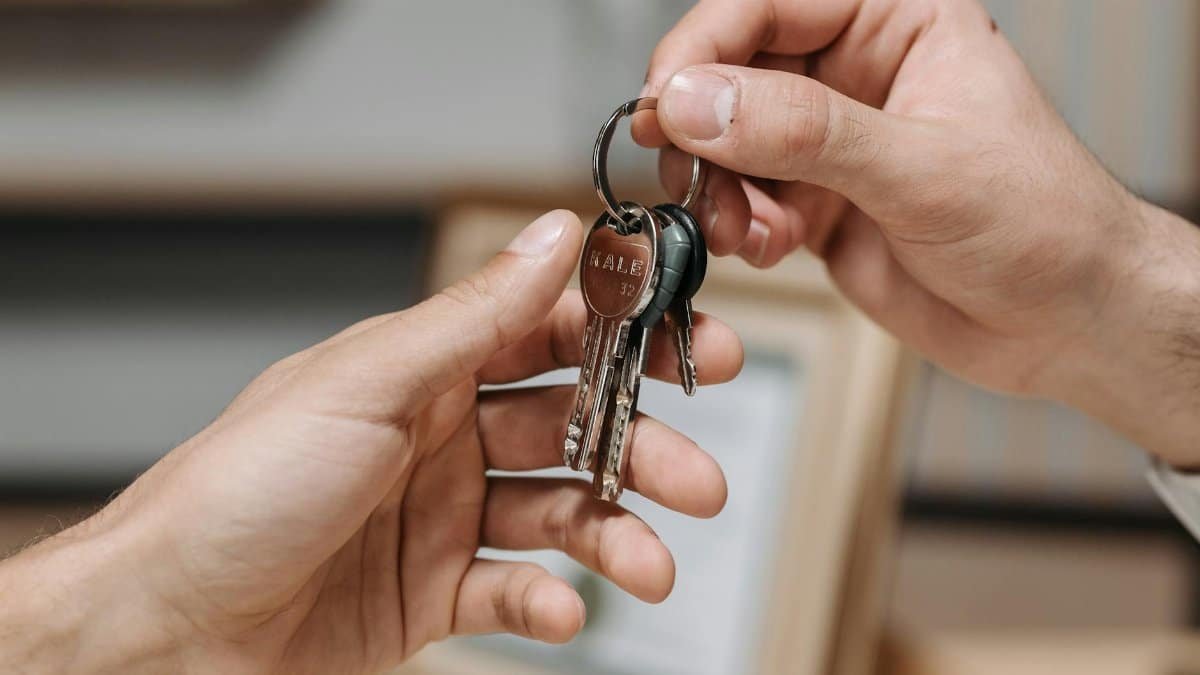 A close-up image of two hands exchanging a set of keys indoors.