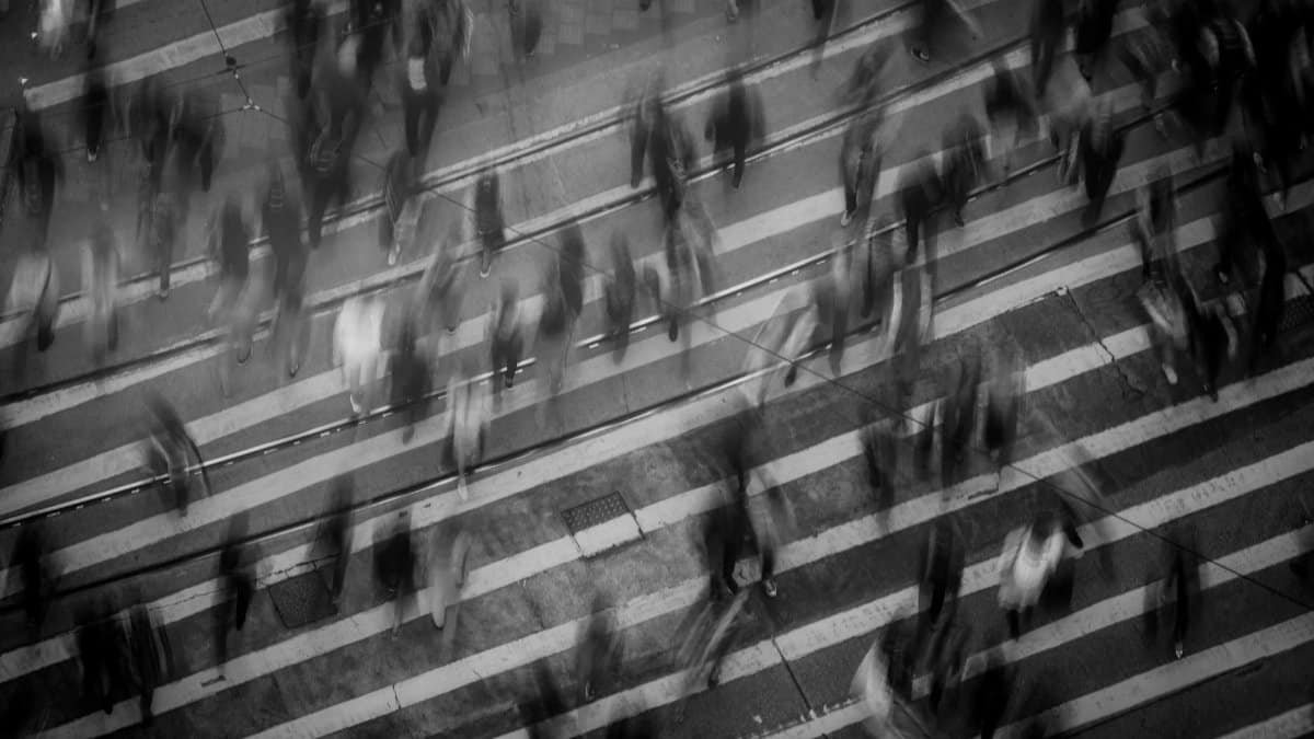 Blurred pedestrians crossing a busy Hong Kong street, showcasing urban movement and dynamics.