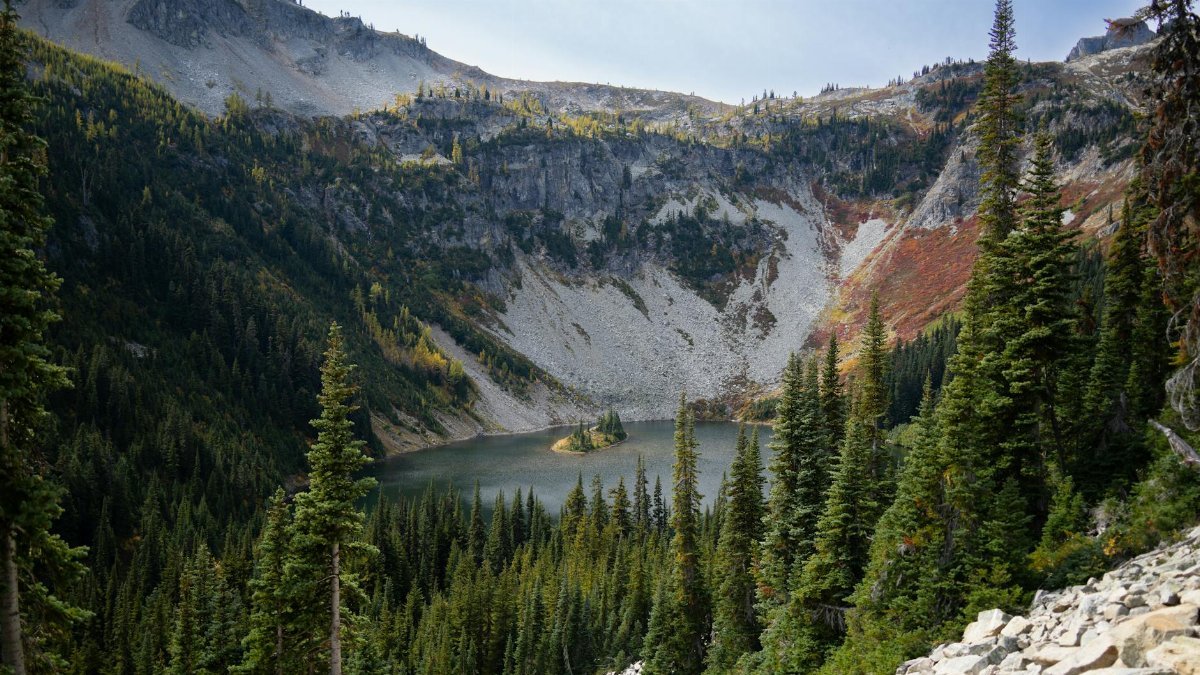 Larch Lake surrounded by autumn trees in the mountainous Washington State wilderness.