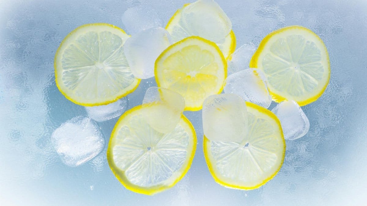 Fresh lemon slices and ice cubes on a cool surface, perfect for refreshment.