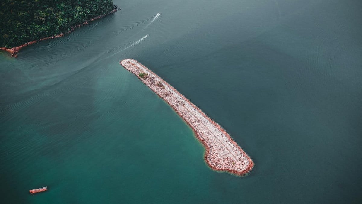 Aerial shot of a small, isolated island surrounded by calm blue waters, perfect for serene exploration.