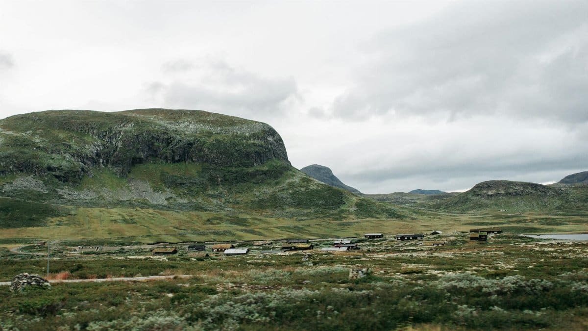 Picturesque mountain landscape with scattered cabins under a cloudy sky.