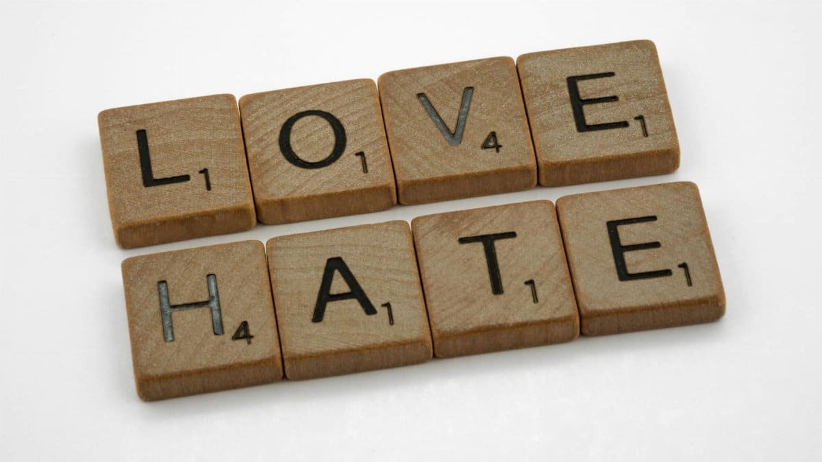 Close-up of wooden Scrabble tiles spelling 'Love' and 'Hate' on a white background.