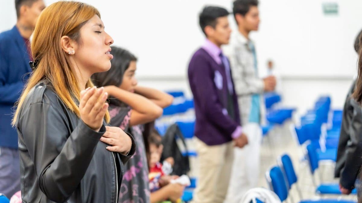 A diverse group of people gathered indoors for a spiritual prayer session in Ciudad de México.