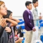 A diverse group of people gathered indoors for a spiritual prayer session in Ciudad de México.