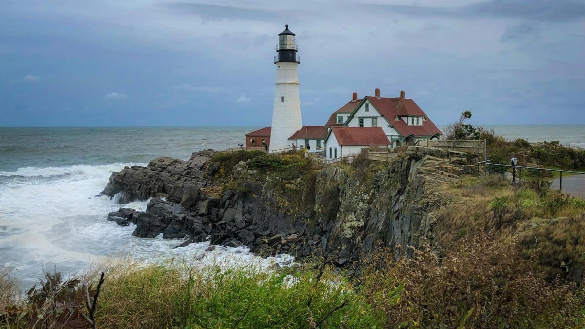Iconic Portland Head Light standing tall on a rugged Maine coastline amidst crashing waves.