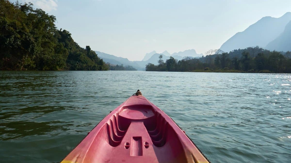 A scenic kayaking journey on a tranquil river in Laos, surrounded by lush landscapes.