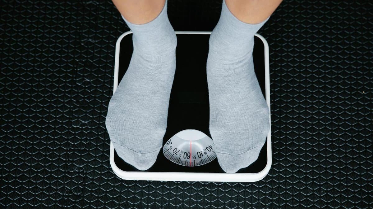 Top view of feet in socks standing on a bathroom scale, indicating weight measurement.