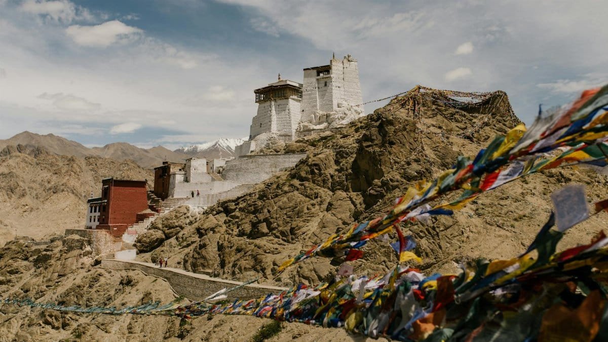 Stunning view of Namgyal Tsemo Monastery in the Himalayas with prayer flags waving in the wind.