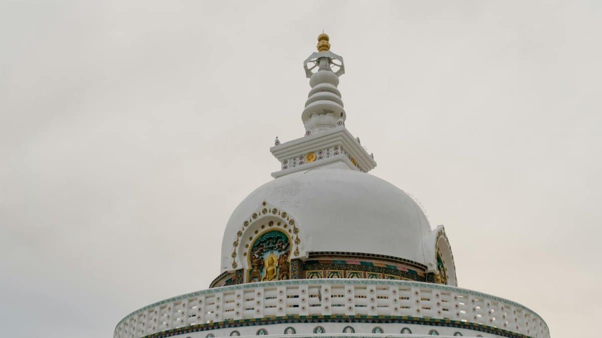 Low angle view of the Shanti Stupa in India with intricate designs against a cloudy sky.