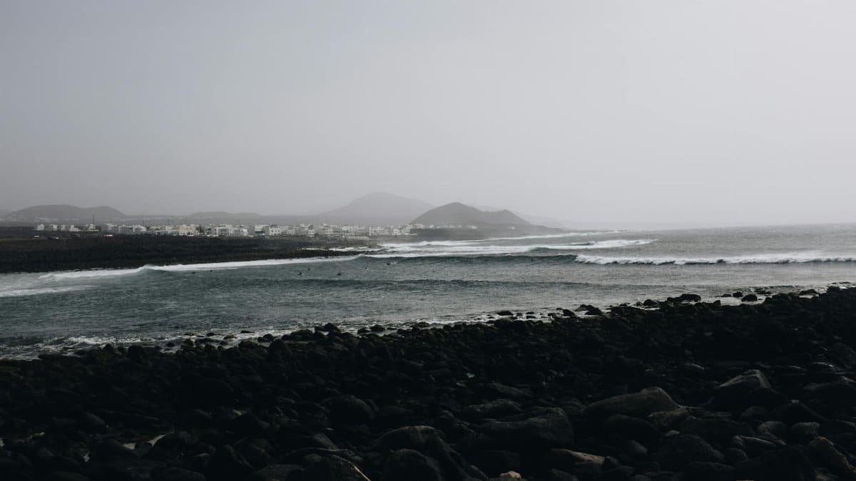 A serene coastal view with waves crashing on rocky shores under an overcast sky.