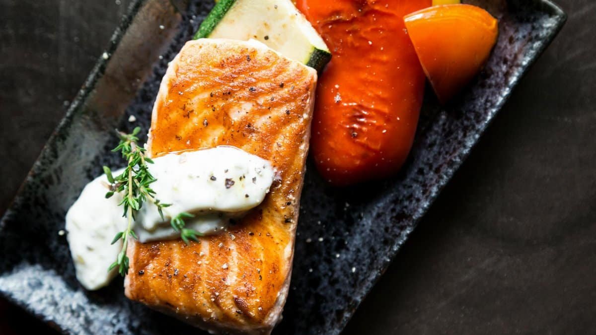 Delicious grilled salmon served with roasted vegetables and herb sauce.