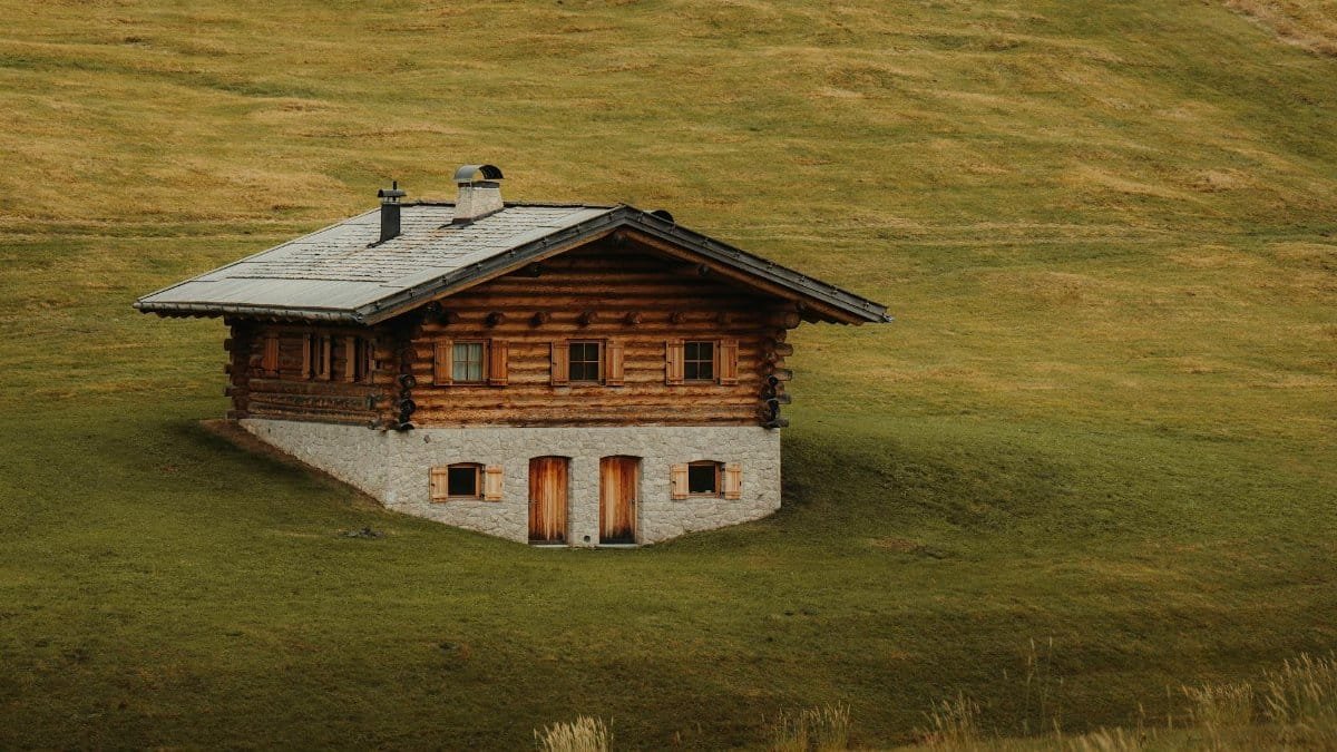 Charming rustic log cabin nestled in lush green hills, perfect for countryside retreats.