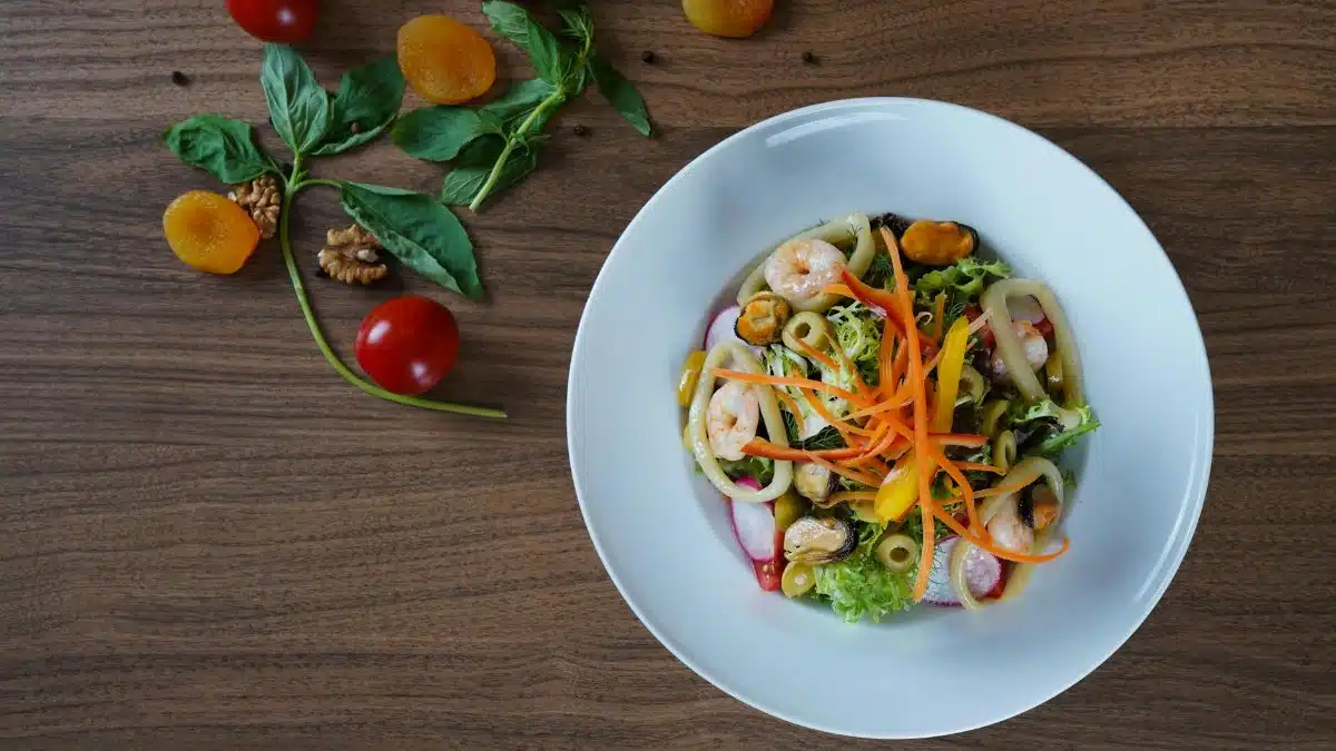 Vibrant seafood salad with shrimp, greens, and colorful vegetables on a rustic setting.