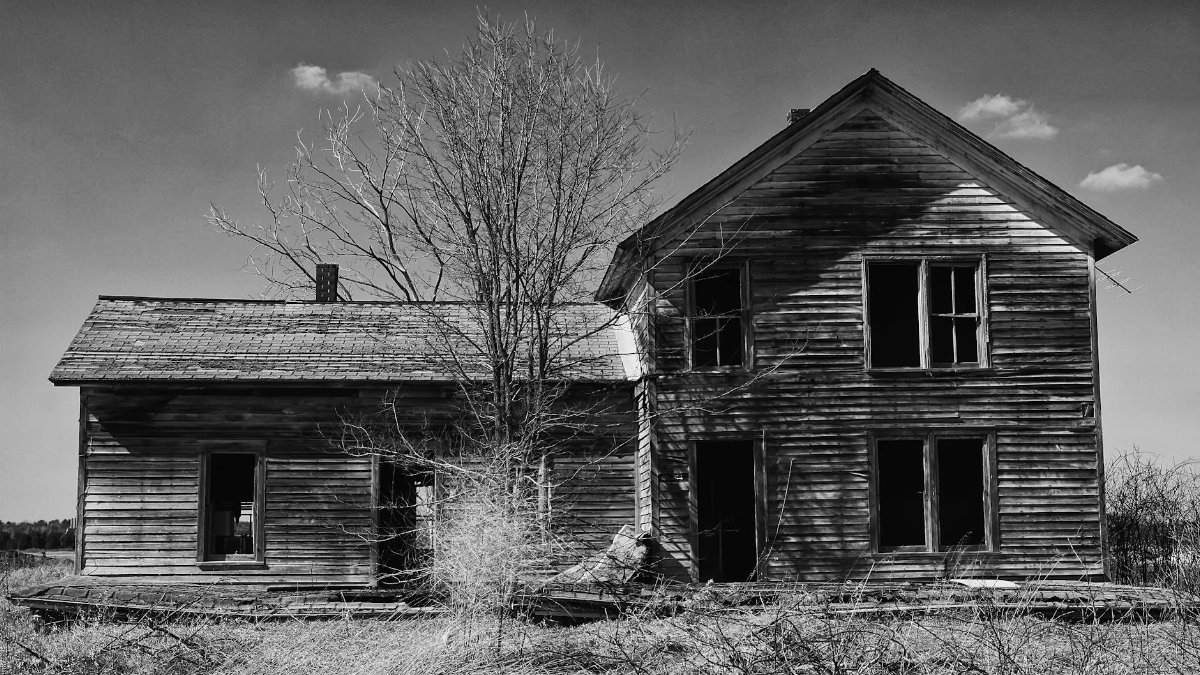 Black and white photo of an old, dilapidated wooden house in rural Marshfield WI.