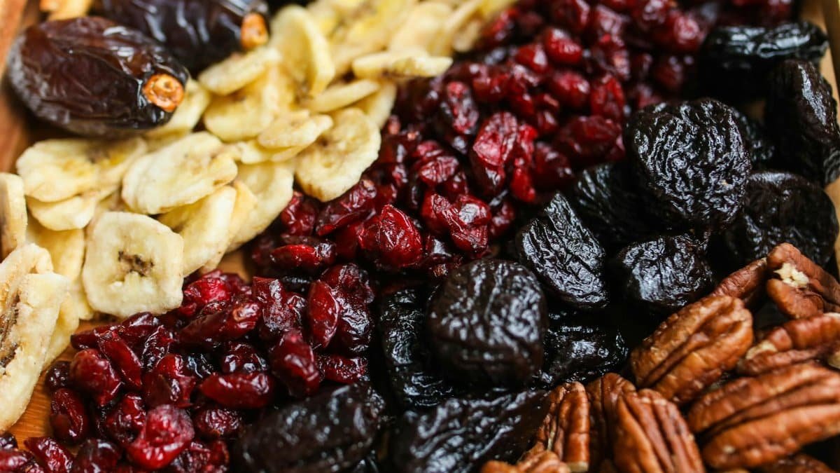 Vibrant mix of dried fruits and nuts on a wooden tray, perfect for healthy snacking.