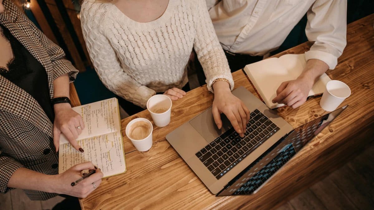 Top view of a collaborative team meeting with laptops and coffee at a wooden table.