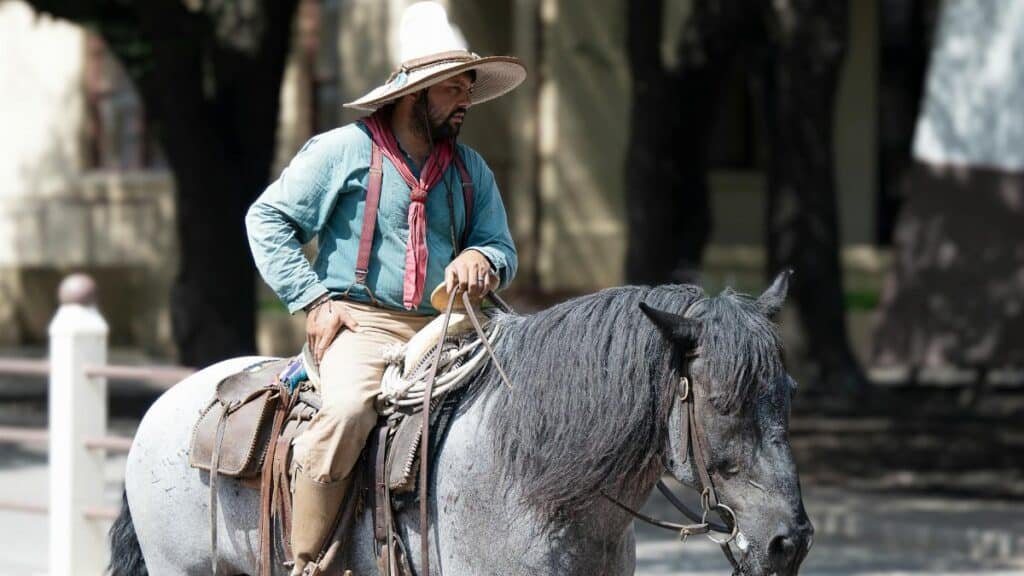 Man in traditional attire riding a black horse in Dallas, Texas.