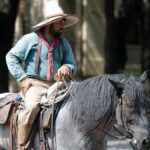 Man in traditional attire riding a black horse in Dallas, Texas.