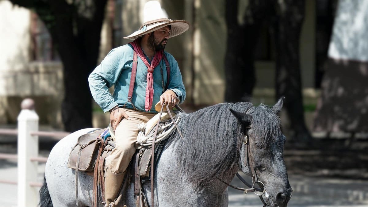 Man in traditional attire riding a black horse in Dallas, Texas.