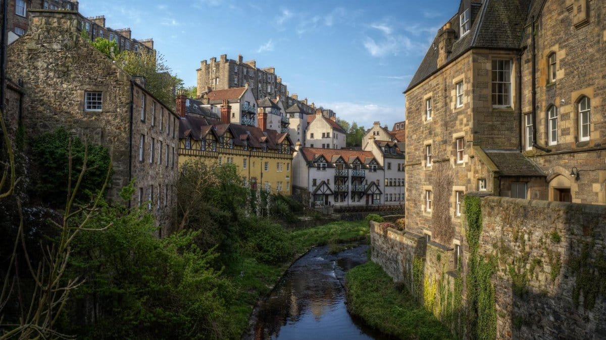 Picturesque view of Dean Village, Edinburgh with historical stone buildings and greenery.