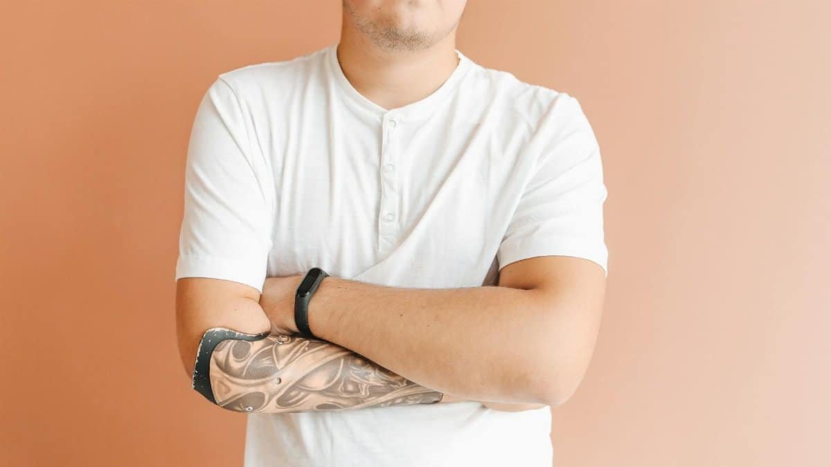 Studio portrait of a man with a prosthetic arm and tattoo, showcasing strength and individuality.