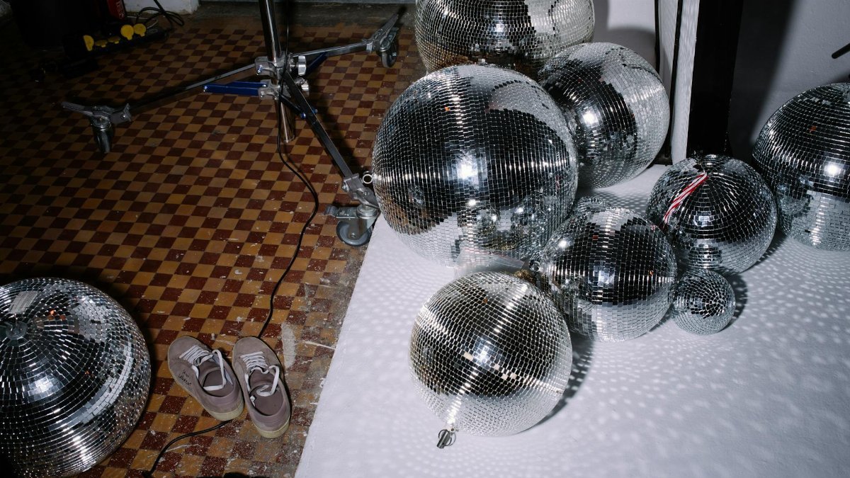 Disco balls scattered on a checkered floor, creating a reflective ambiance.