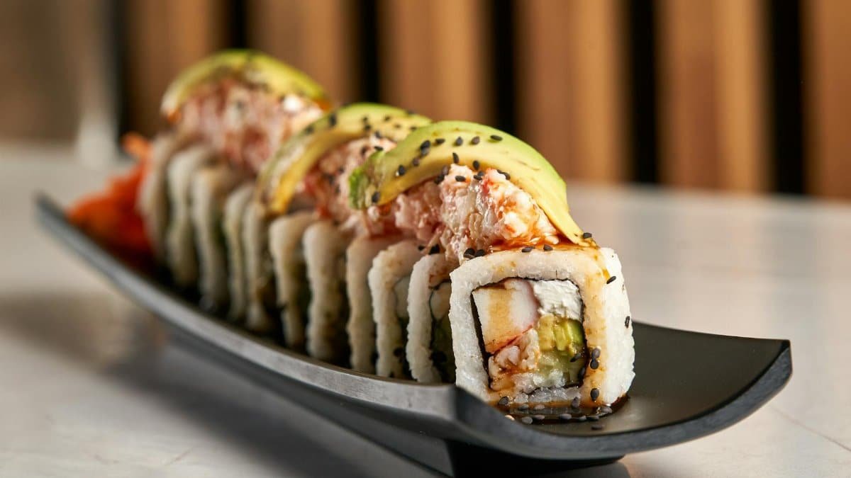 Delicious sushi roll with avocado and crab, garnished with black sesame seeds.