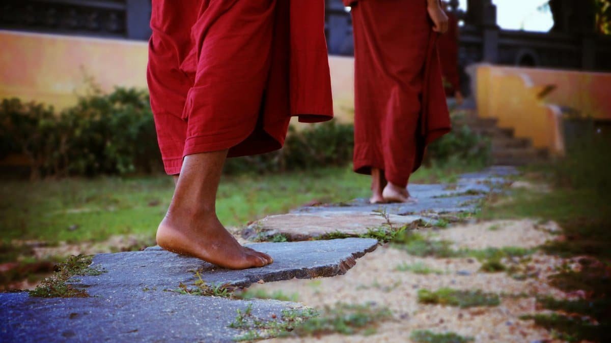 Buddhist monks walking barefoot on a stone path in Matara, Sri Lanka.