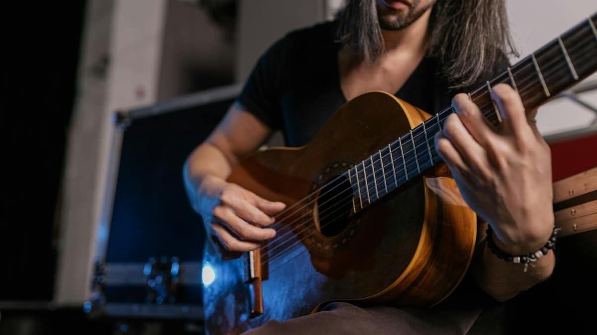 Unrecognizable musician strumming an acoustic guitar during a live performance.
