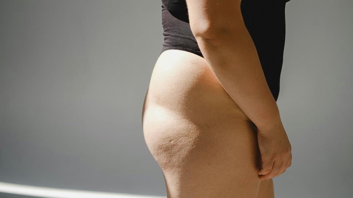 Profile view of a woman's body in natural light showcasing skin texture and curves.