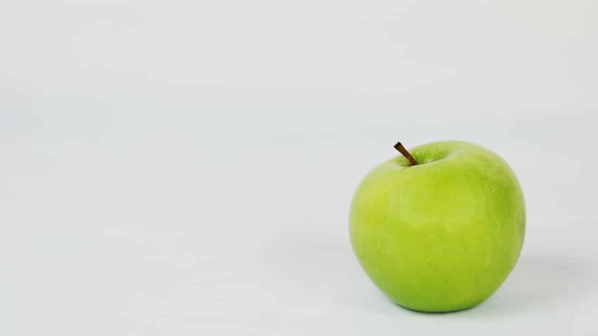 A single green apple placed against a crisp white background, perfect for food photography.