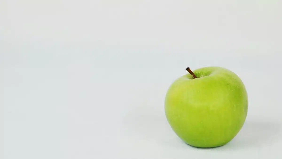 A single green apple placed against a crisp white background, perfect for food photography.