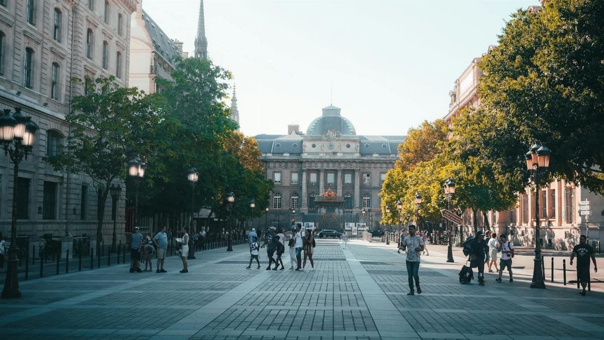 A bustling Parisian street scene with historic architecture and people enjoying a sunny day.
