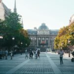 A bustling Parisian street scene with historic architecture and people enjoying a sunny day.