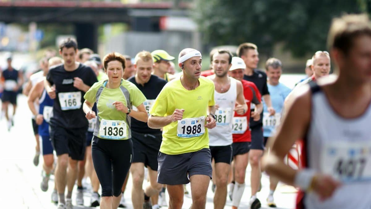 A diverse group of runners actively participating in a marathon on a city street during the day.