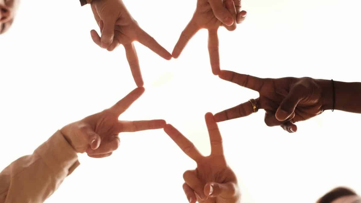 A group of diverse hands forming a star shape, symbolizing unity and friendship.
