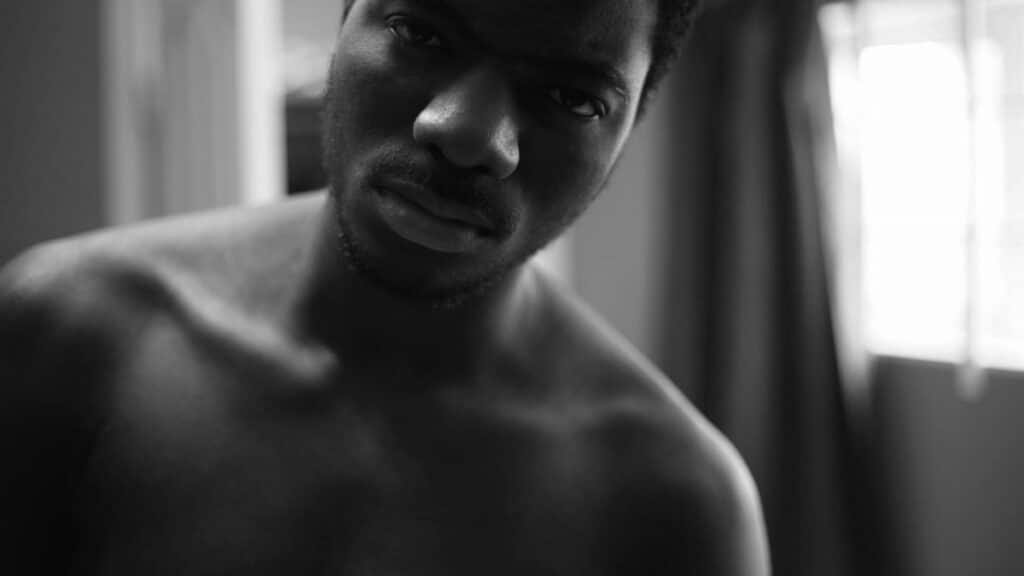 Black and white close-up of a thoughtful man in soft lighting.