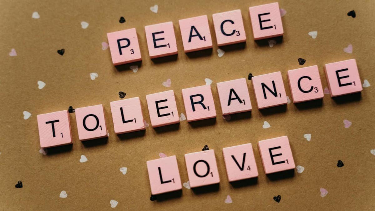 Pink tiles on a polka dot background spelling peace, tolerance, and love.