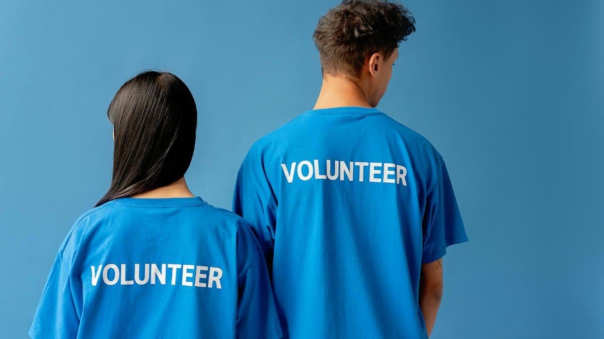 Two people wearing blue volunteer shirts standing against a blue background.