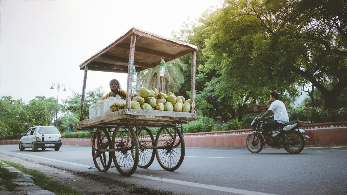 A coconut seller with a cart on a busy street in Jaipur, India, capturing daily life.