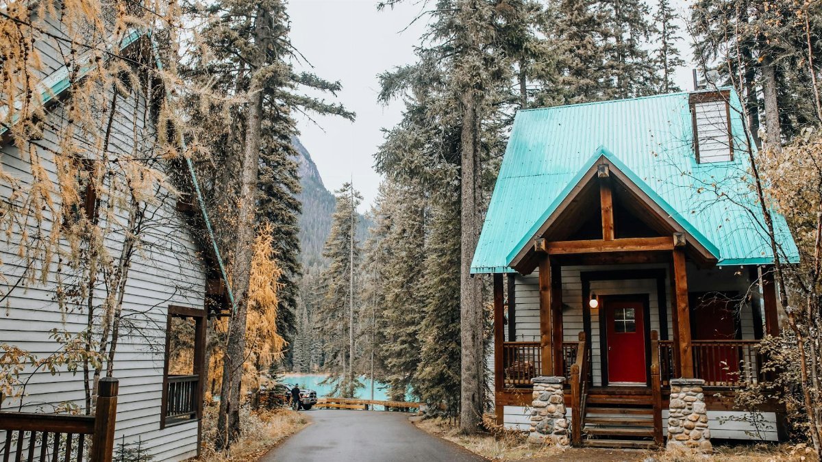 Idyllic forest scene with cozy cabins, turquoise roofs, and serene nature.