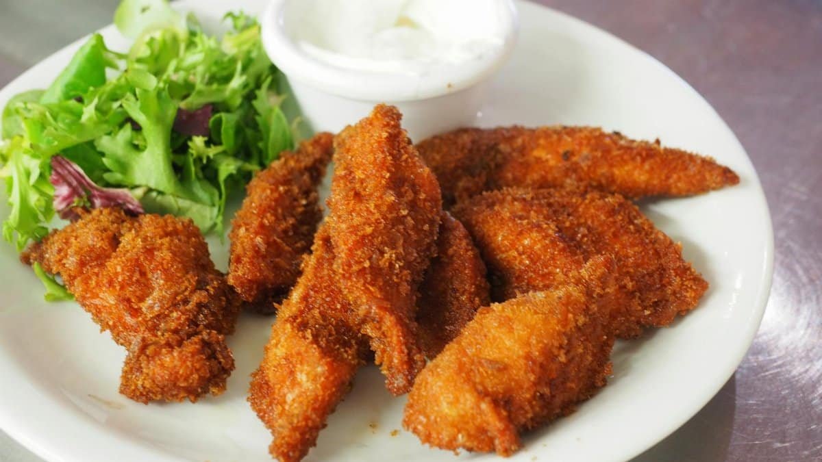 Delicious crispy fried chicken tenders served with a fresh green salad and dipping sauce.