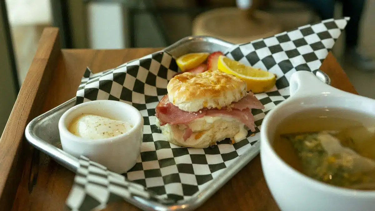 A delicious ham and cheese biscuit served with lemon slices and tea, perfect for breakfast.