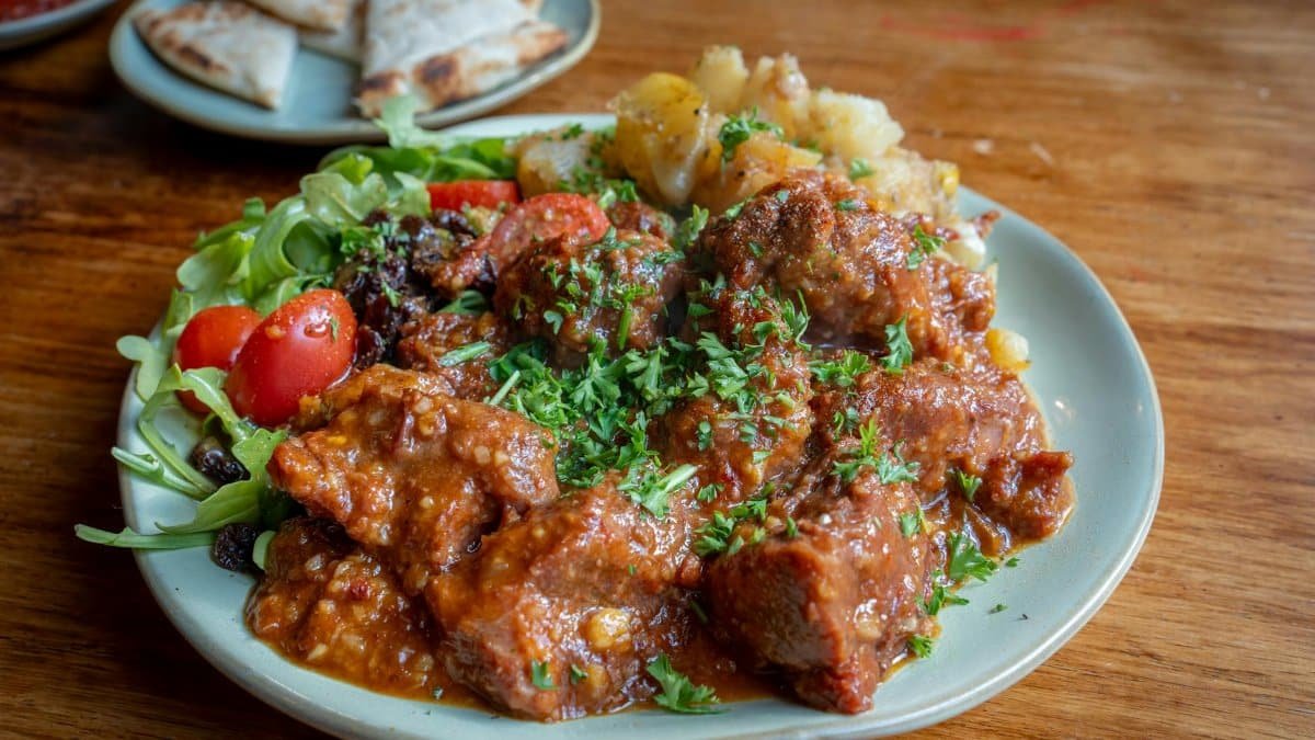 Savor a hearty beef stew with fresh cherry tomatoes and greens, perfect for lunch.