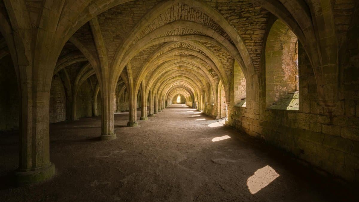 Explore the historic gothic arches of Fountains Abbey, England.