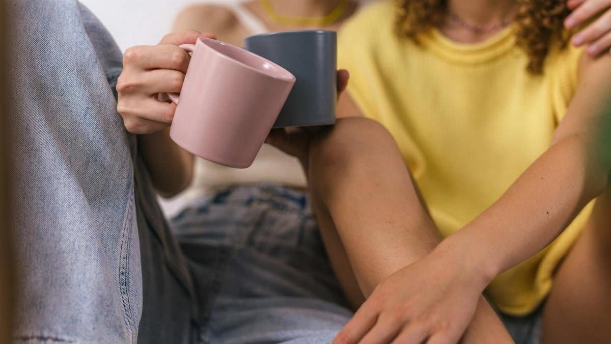 Close-up of a couple holding mugs, sharing a warm moment indoors.