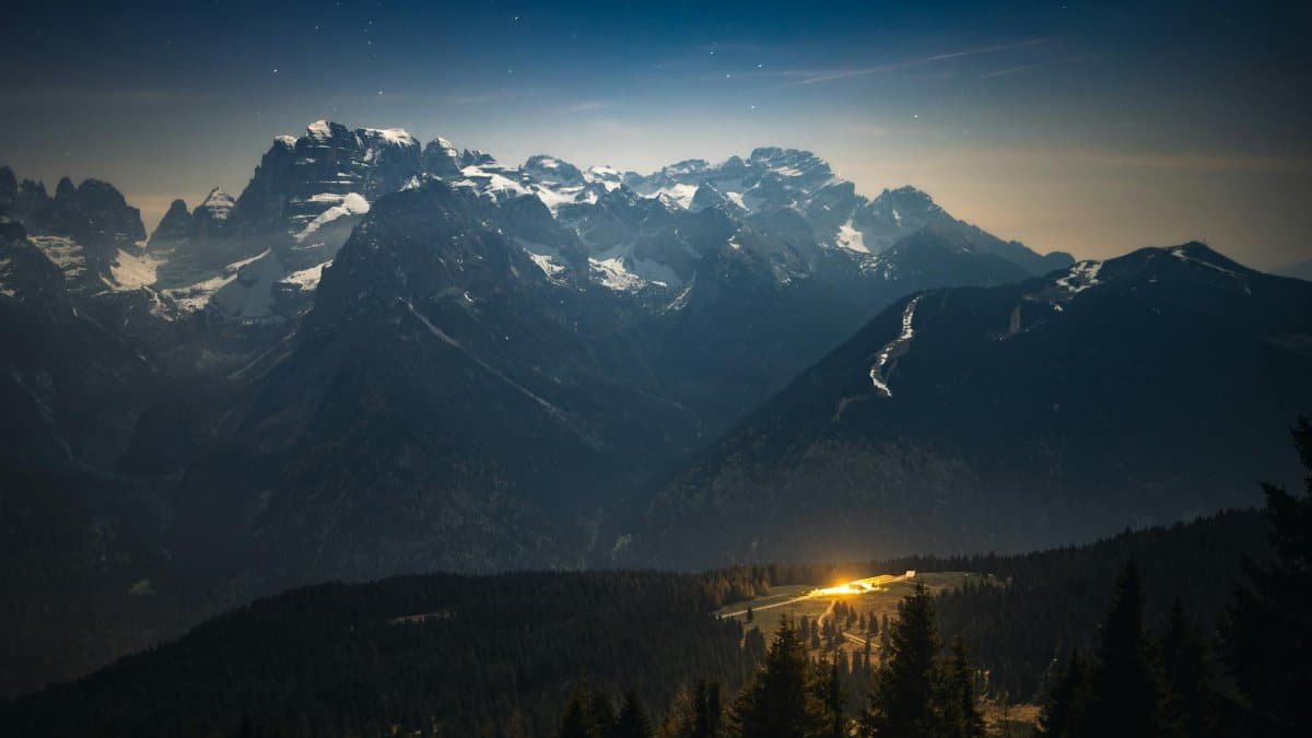 Stunning astrophotography showcasing the Milky Way over snow-capped Italian Alps at night.