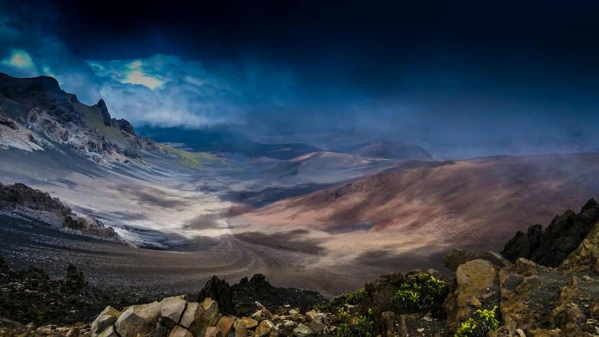 A breathtaking view of Haleakalā Crater in Maui, Hawaii, taken at dusk with dramatic clouds and rocky terrain.