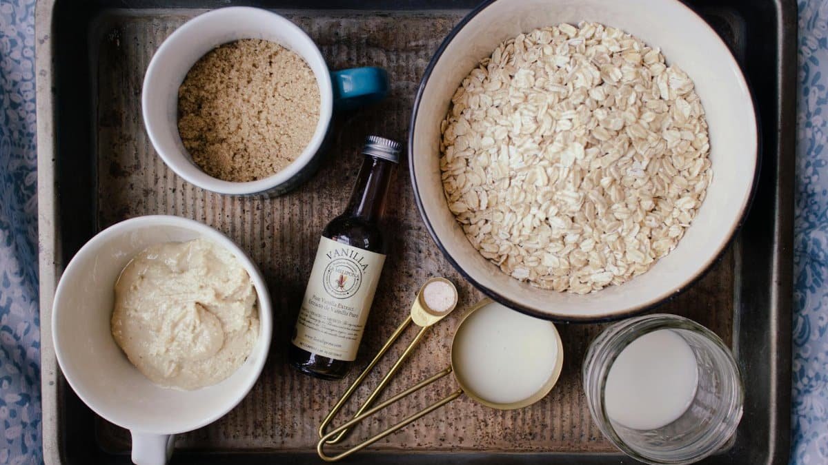 A flat lay of ingredients for oatmeal cookies, including oats, brown sugar, and vanilla.